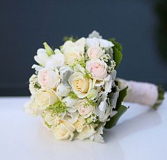 Бело-кремовый букет невесты — Бело-кремовый букет невесты. Нежный круглый шарик из кремовых роз, белых тюльпанов, нежной зелени алхемиллы с манжеткой из серебристых листиков цинерарии и кожистых листьев галакса. Ножка букета задекорирована кремовой атласной лентой.