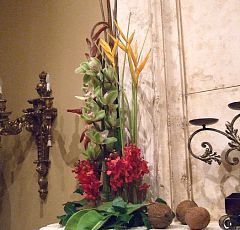 Цветочное оформление детского праздника "Мадагаскар" — Композиции на камин. Причудливая геликония, яркие орхидеи мокара, восковые цветы цимбидиума, сочно-зеленые листья фикуса, кокосовые орехи.