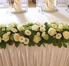 Стол жениха и невесты Бело-зеленая классика — Композиция на стол жениха и невесты в классической бело-зеленой гамме. Белоснежные минигерберы, крупные садовые розы аваланж, зеленые гвоздика и гортензия.